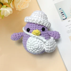 Complete purple penguin crochet plush kit supplies on wooden table